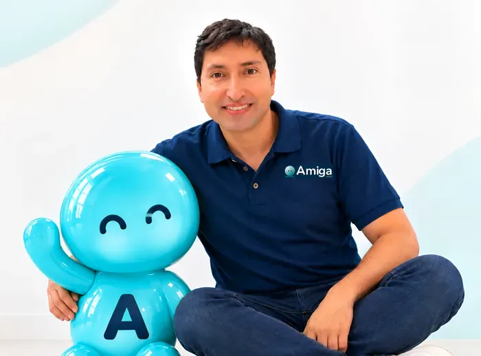 El fundador de Amiga HSEQ sentado en el piso junto a Ami, la asistente de la marca, que saluda con la mano